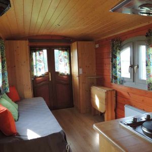 Hébergement insolite en Limousin : charmante roulotte en bois avec rideaux colorés.