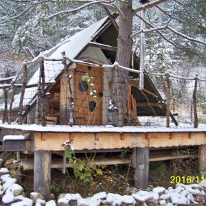 Cabane en bois sur pilotis, entourée de neige, au cœur de lAuvergne-Rhône-Alpes.