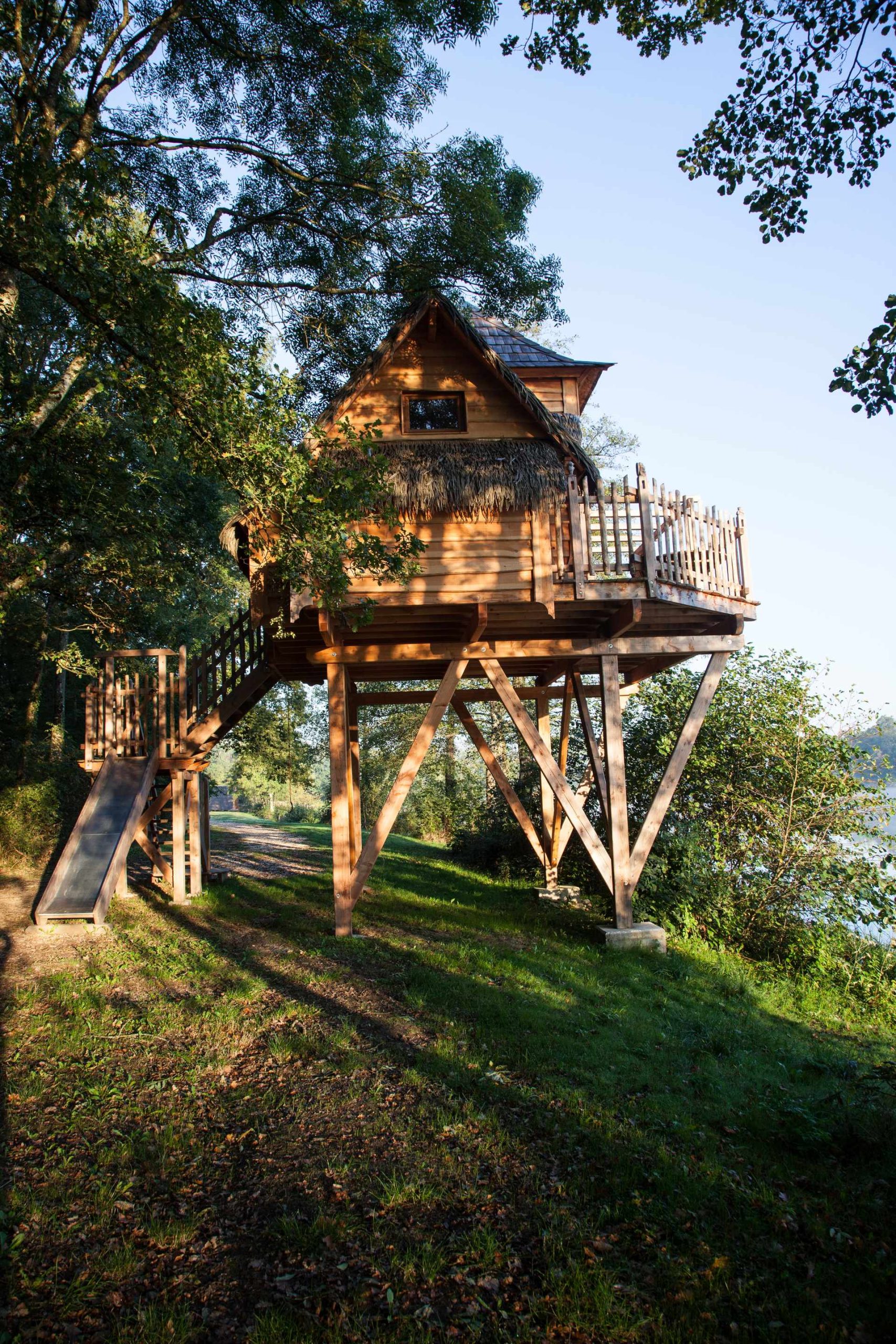 2015-09-30_21 Cabane perchée en bois, entourée darbres, offrant une vue sur leau.