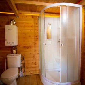 Cabane en bois avec salle de bain moderne, douche et toilettes intégrées.