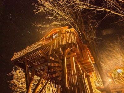 Cabane perchée en Aquitaine, illuminée sous un ciel étoilé.
