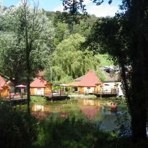 Hébergement insolite en cabanes en bois au bord dun étang, entouré darbres.