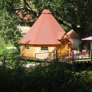 Cabane en bois avec toit en pointe, entourée dun cadre naturel paisible.