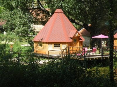 Cabane en bois avec toit en pointe, entourée dun cadre naturel paisible.