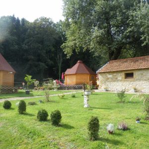 Hébergement insolite en cabanes en bois, entouré dun jardin verdoyant et fleuri.