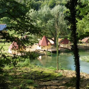 Hébergement insolite en cabanes au bord dun lac, entouré de verdure.