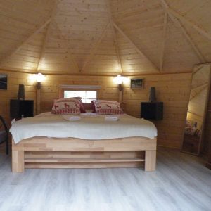 Cabane en bois à Champagne-Ardennes, intérieur chaleureux avec lit double et décor rustique.
