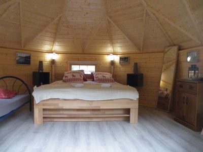Cabane en bois à Champagne-Ardennes, intérieur chaleureux avec lit double et décor rustique.