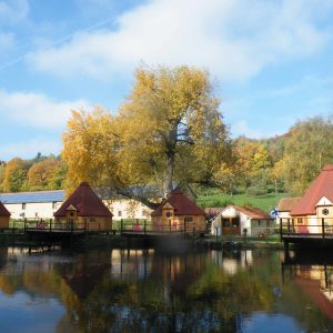 Hébergement insolite en cabanes au bord dun étang, entouré darbres colorés.