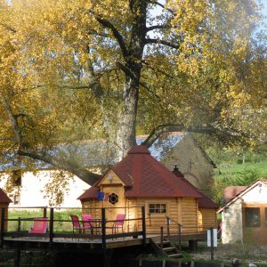 Cabane en bois au bord de leau, entourée darbres aux feuilles dorées.