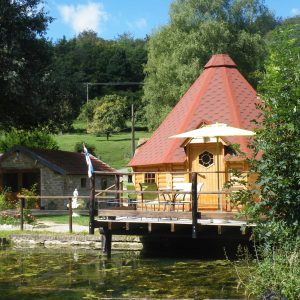Cabane en bois avec toit en tuiles, terrasse au bord de leau à Champagne-Ardennes.