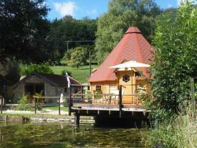 Cabane en bois avec toit en tuiles, terrasse au bord de leau à Champagne-Ardennes.