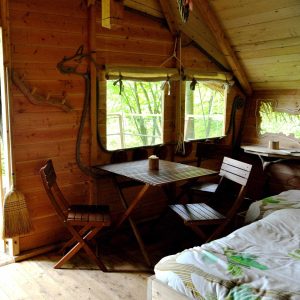 Cabane en bois en Haute-Normandie avec table et chaises en intérieur chaleureux.