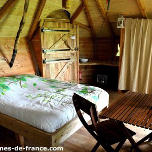 Cabane en bois à Haute-Normandie, avec lit douillet et coin repas en bois.