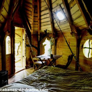 Cabane en bois cosy avec fenêtres arrondies et mobilier en bois naturel.