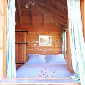 Cabane en bois avec lit douillet et décorations de papillons aux murs.
