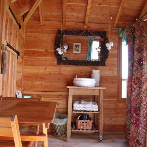Intérieur chaleureux dun hébergement insolite en bois, avec table et miroir décoratif.