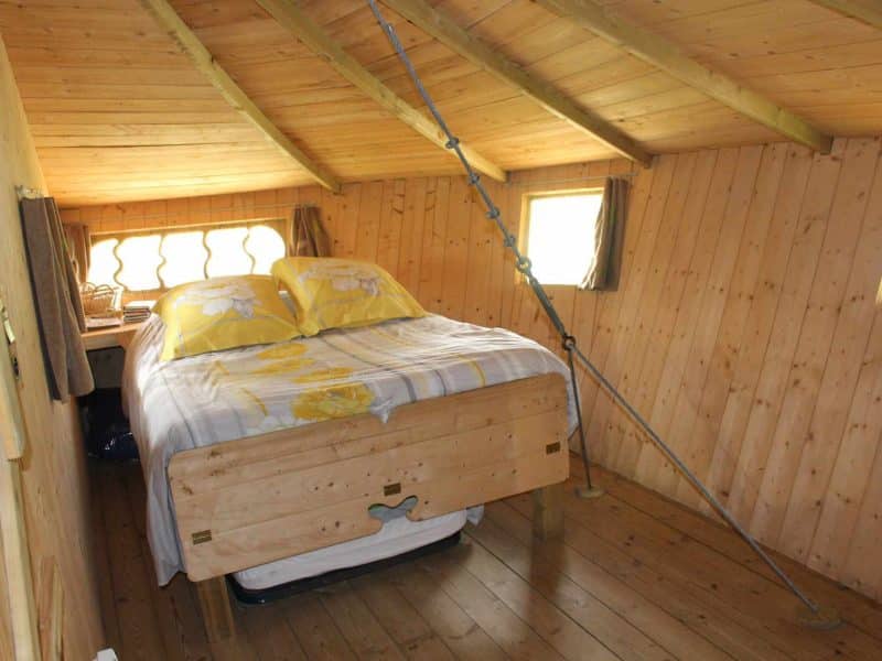 Chalet en bois avec lit double et décoration chaleureuse, ambiance cosy.