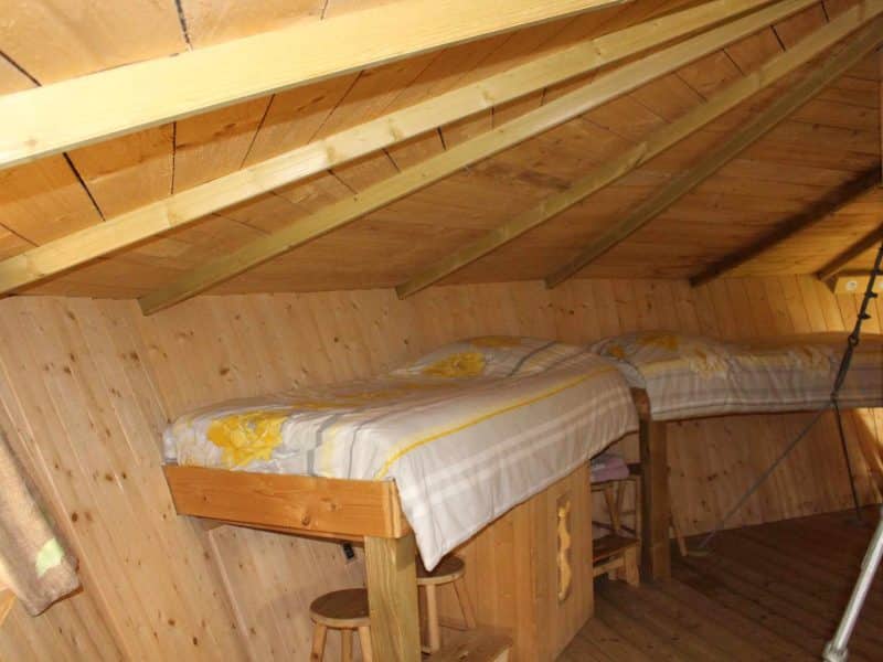 Chalet en bois avec lits jumeaux, ambiance chaleureuse et naturelle.