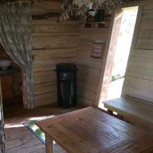 Cabane en bois dans les arbres, avec table en bois et vue sur la nature.