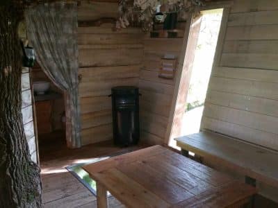 Cabane en bois dans les arbres, avec table en bois et vue sur la nature.