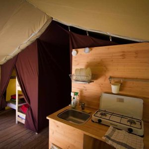 Tente safari spacieuse avec kitchenette et lits superposés, idéale pour un séjour nature.