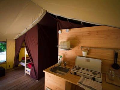 Tente safari spacieuse avec kitchenette et lits superposés, idéale pour un séjour nature.