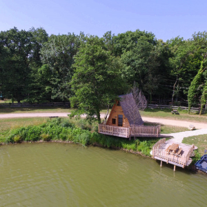 Cabane en bois au bord dun lac, entourée de verdure en Auvergne-Rhône-Alpes.