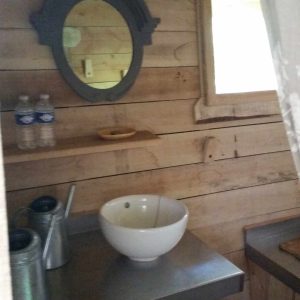 Cabane en bois dans les Pays de la Loire, avec lavabo en céramique et miroir vintage.