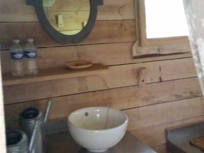 Cabane en bois dans les Pays de la Loire, avec lavabo en céramique et miroir vintage.