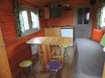 Cabane en bois à Limousin, intérieur chaleureux avec table en bois et coussins colorés.