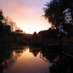 Hébergement insolite en cabanes au bord de leau, avec un coucher de soleil éclatant.