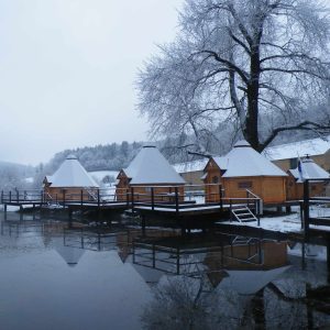 Hébergement insolite en chalets en bois au bord dun lac, sous la neige.