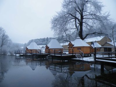 Hébergement insolite en chalets en bois au bord dun lac, sous la neige.