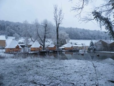 Cabane sur pilotis en Champagne-Ardenne, entourée de neige et dun paysage hivernal.