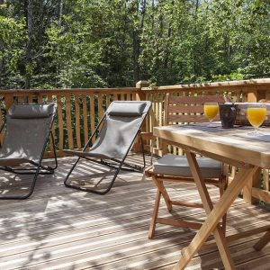 Hébergement insolite en Auvergne-Rhône-Alpes avec terrasse en bois et chaises longues.