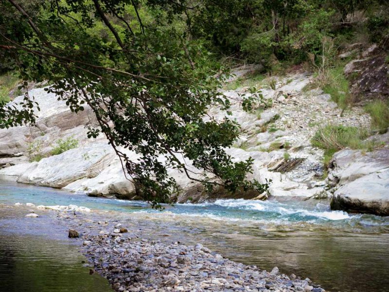Hébergement en bord de rivière, entouré de rochers et de verdure apaisante.