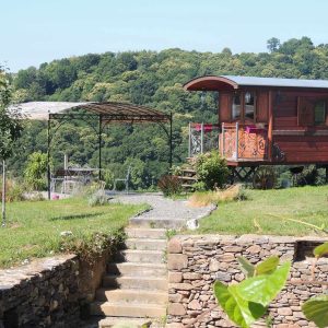 Charmante roulotte en bois, entourée de verdure et offrant une vue panoramique.
