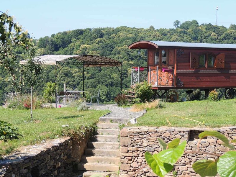 Charmante roulotte en bois avec terrasse, entourée de verdure et de paysages pittoresques.