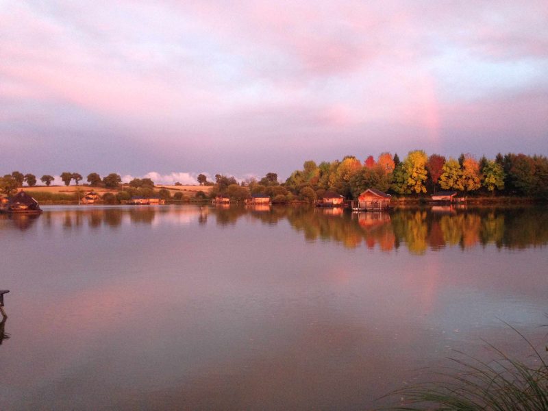 Chalets au bord dun lac, entourés darbres aux couleurs dautomne.