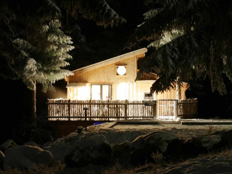 Chalet lumineux en bois, entouré de neige, offrant un cadre paisible en Bourgogne-Franche-Comté.