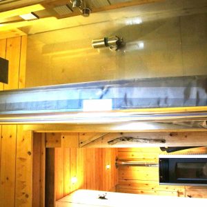 Hébergement insolite en bois avec baignoire moderne et éclairage chaleureux.