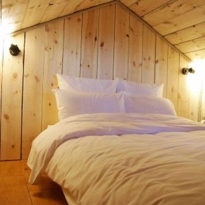 Chambre en bois dans un hébergement insolite en Bourgogne-Franche-Comté, ambiance chaleureuse.