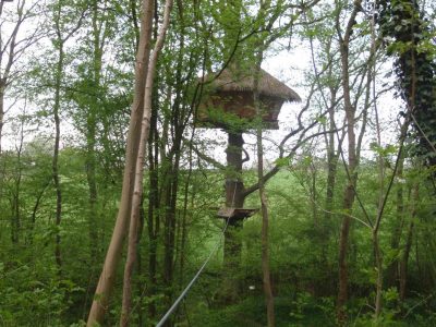 Cabane perchée dans les arbres, entourée de verdure luxuriante en Haute-Normandie.