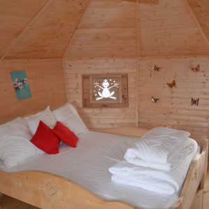 Cabane en bois avec lit douillet et décorations murales colorées.