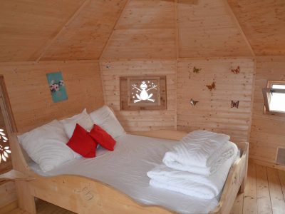 Cabane en bois avec lit douillet et décorations murales colorées.