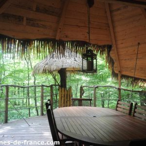 Cabane perchée en bois avec terrasse, entourée de verdure en Haute-Normandie.