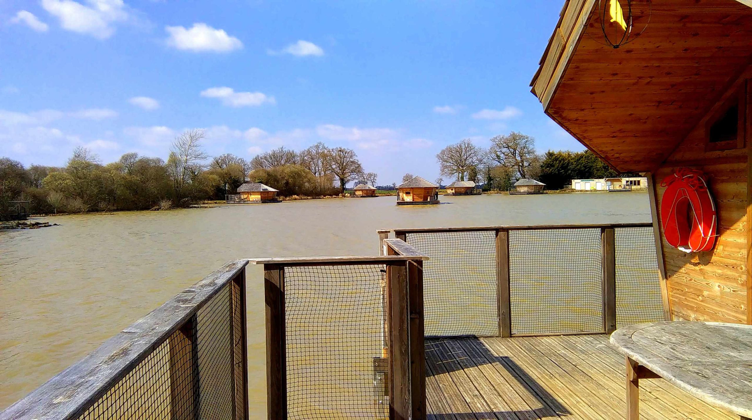 IMAG0492 Cabane flottante en Nouvelle-Aquitaine, vue sur un lac paisible et des arbres.