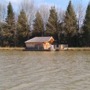 Cabane flottante en bois sur leau, entourée darbres en Nouvelle-Aquitaine.