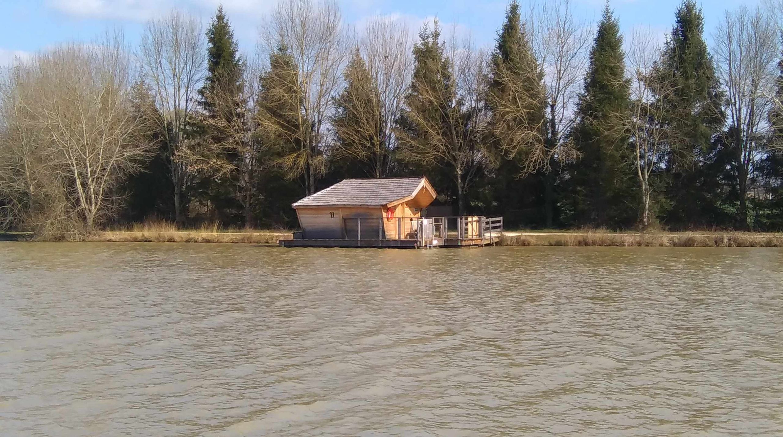 IMAG0574 Cabane flottante en bois sur leau, entourée darbres en Nouvelle-Aquitaine.